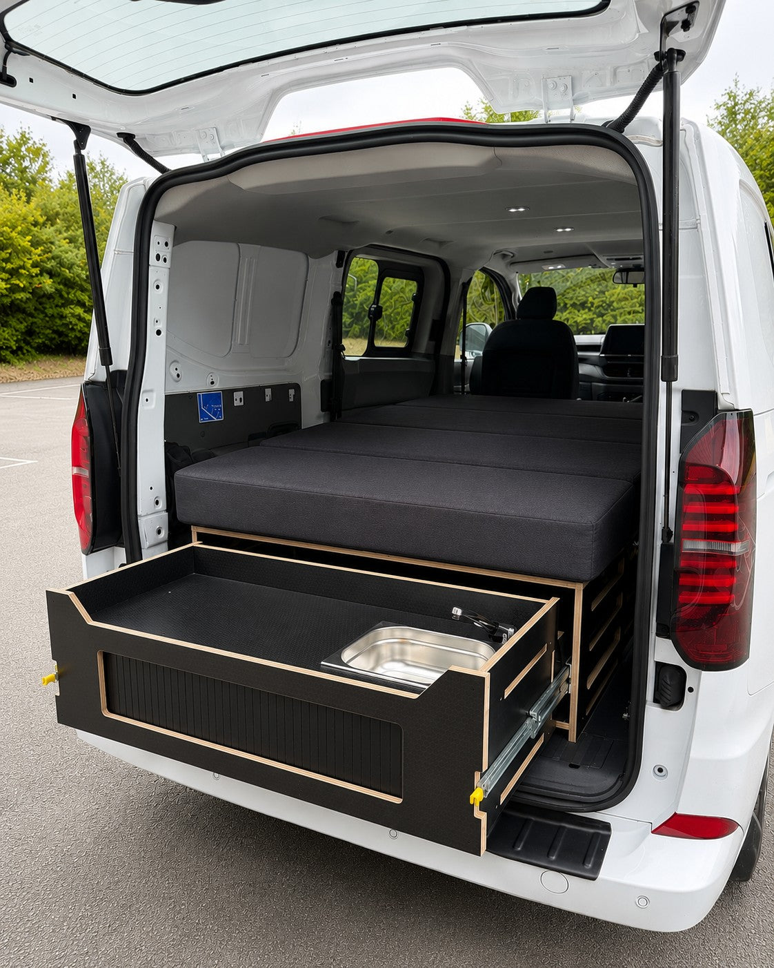 Discovery pod in a van with the bed made up and the kitchen drawer pulled out